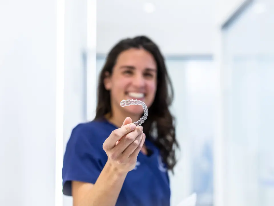 Paciente sonriendo con un alineador Invisalign en la mano